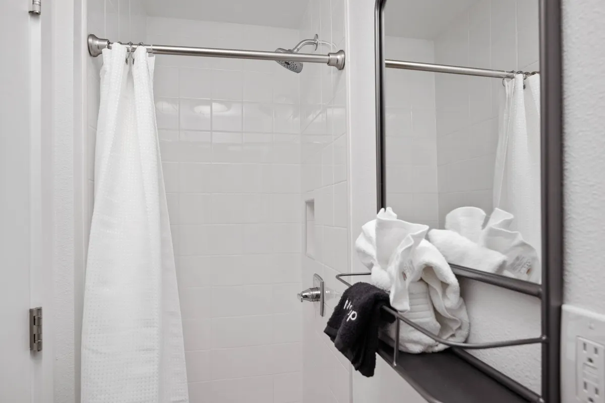 A bright and modern shower area with fresh towels neatly arranged on a rack and a large mirror, conveying a sense of post-beach refreshment and comfort.